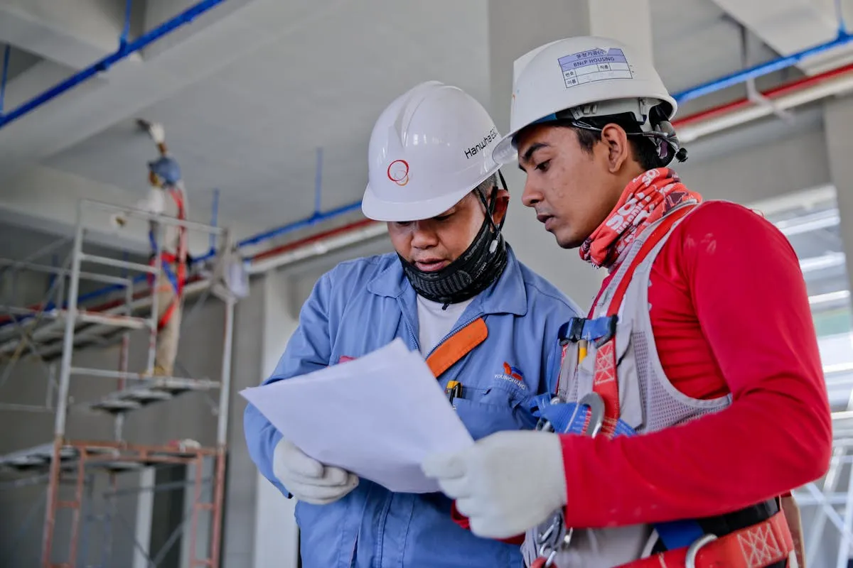 Construction workers reviewing site plans with hard hats and safety gear